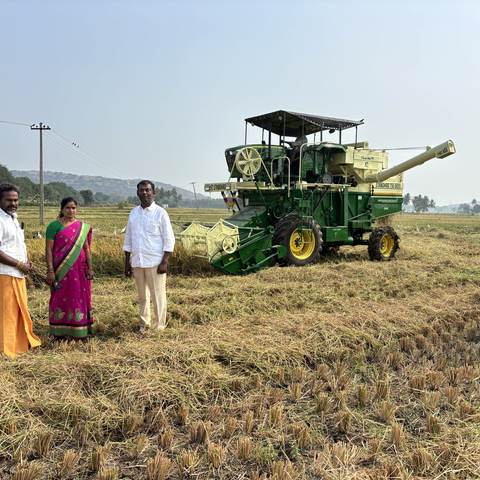 A farmer family standing beside a harvester at the end of the season.