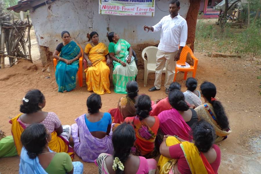 A women's self-help group seated outdoors at a financial literacy session, N.M. Kulam.