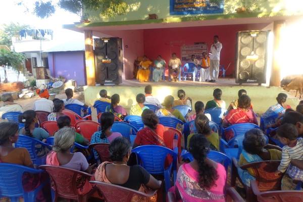 A village assembly held in the open, women seated at the front.
