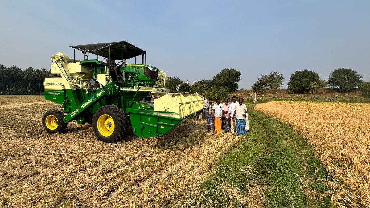 Foundation leaders and farmers reviewing a harvest, standing field-side beside a combine.