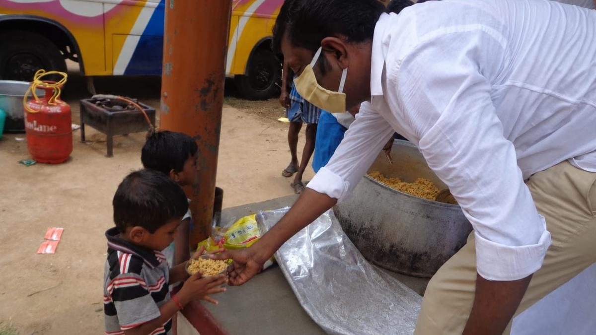 A Foundation volunteer sharing a meal with children at a community relief point.